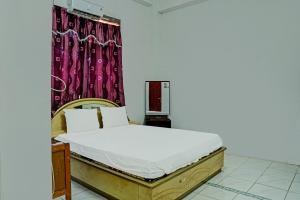 a bedroom with a bed and a red curtain at Hotel O Kost Axcel in Banjarmasin
