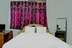 a bedroom with a large bed and a window at Hotel O Kost Axcel in Banjarmasin
