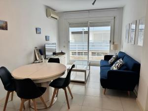 un soggiorno con un tavolo e un divano blu di Apartamento a 100 metros de la playa con aire acon a Tossa de Mar