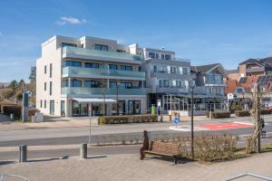 ein Gebäude mit einer Bank vor einer Straße in der Unterkunft Strandallee - Ferienapartments direkt am Strand von Haffkrug in Haffkrug