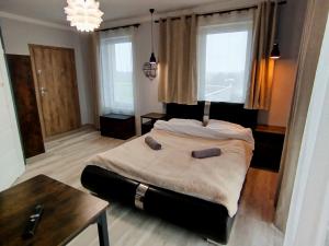ein Schlafzimmer mit Bett, Tisch und Fenstern in der Unterkunft Malownicze Owieczki 