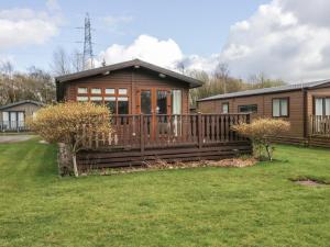 a log cabin with a large deck in a yard at Gressingham View Lodge in Carnforth