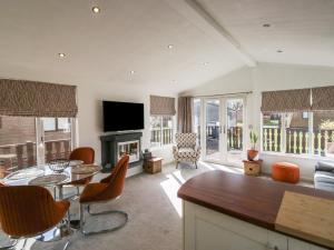 a living room with a television and a table and chairs at Gressingham View Lodge in Carnforth