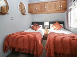 a bedroom with two beds with red blankets and a mirror at Gressingham View Lodge in Carnforth