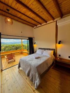a bedroom with a large bed and a large window at Cabana Bariloche - Busch Camping in Rancho Queimado