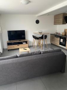 a living room with a gray couch and a kitchen at appartement avec 2 suites parentales in Angoulême