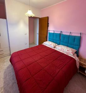 a bedroom with a red bed with a blue head board at Villa Nausica fronte mare - A in Torre Lapillo