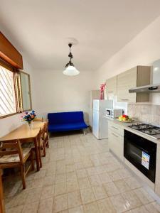 a kitchen with a table and a blue couch in it at Villa Nausica fronte mare - A in Torre Lapillo