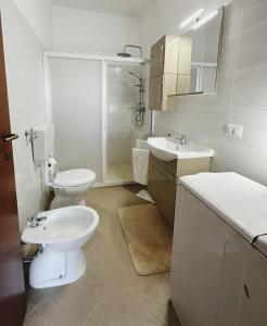 a white bathroom with a toilet and a sink at Villa Nausica fronte mare - A in Torre Lapillo +3 photos