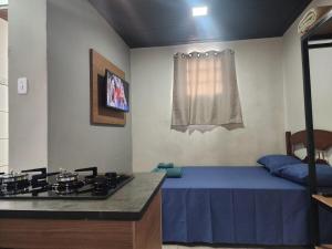 a room with a kitchen with a stove and a bed at Kitnet mobiliada em Lins in Lins +6 photos