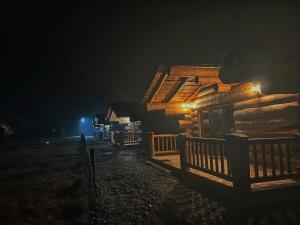 a log cabin at night with lights on it at EastWood Cabins in Moisei