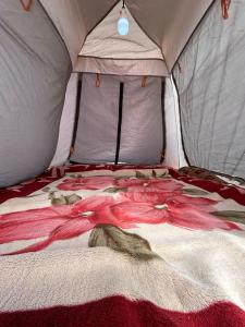 a bed in a tent with a blanket on it at Wadi Rum Paris Cave in Wadi Rum