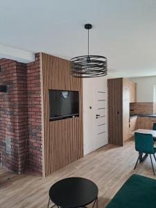 a living room with a tv and a brick wall at Domek letniskowy Leśne Zacisze- jacuzzi, balia ogrodowa, grill i altana in Słopnice