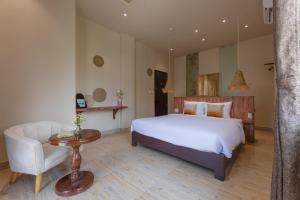 a bedroom with a bed and a couch and a chair at Vaia Hoi An Boutique Hotel in Hoi An
