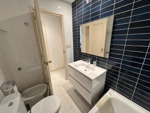 un bagno piastrellato blu con lavandino e WC di Apartamento a 100 metros de la playa con aire acon a Tossa de Mar