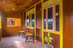 a porch of a house with two chairs and a plant at Hotel O Filadelfia Resto & Penginapan Near Benteng Moraya in Manado +19 photos