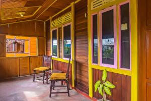 a porch of a house with two chairs and windows at Hotel O Filadelfia Resto & Penginapan Near Benteng Moraya in Manado