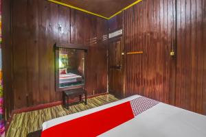 a wooden room with a bed and a mirror at Hotel O Filadelfia Resto & Penginapan Near Benteng Moraya in Manado