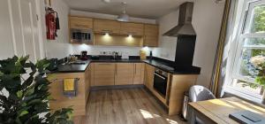 a kitchen with wooden cabinets and a black counter top at Apartment Ivy - Part of the The Bay Filey Holiday Village with pool, gym and direct beach access, pub, restaurant, tennis and meadows walks in Filey +34 photos