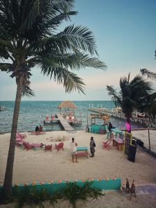 a beach with palm trees and people on the beach at Barefoot Beach Belize in Caye Caulker
