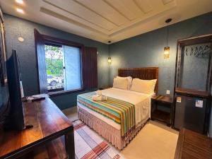 a bedroom with a bed and a tv and a window at Suítes Sal da Terra in Cabo Frio