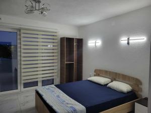 a bedroom with a blue bed and a window at Jordanovi Premium Apartment in Kavadarci