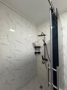 een badkamer met douche en witte marmeren muren bij Аpartment in Samarkand