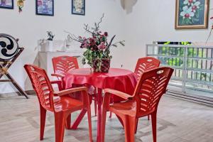 une table rouge avec des chaises rouges et un vase de fleurs. dans l'établissement Hotel O Mariko's House, à Kupang