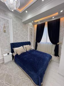 een slaapkamer met een blauw bed en een kroonluchter bij Аpartment in Samarkand