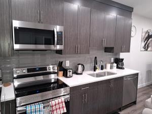 a kitchen with a stainless steel stove and a microwave at Cozy 2 Bedroom Walkout Basement in YYC