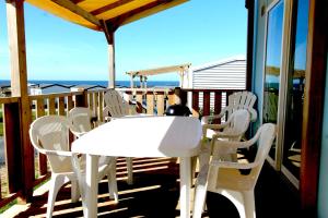 a white table and chairs on a deck with the ocean at BluePortel Location Mobil-home Le Portel Bord de Mer in Le Portel