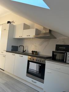 a kitchen with white cabinets and a stove top oven at Bane Apartments 95qm - Messewohnung, Ferienwohnung,Monteurwohnung in Hannover