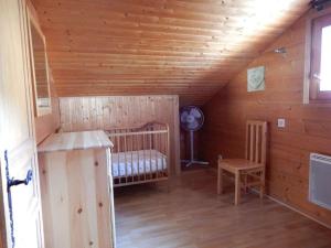 a room with a crib and a chair in a cabin at Chalet des FURETS in Xonrupt-Longemer
