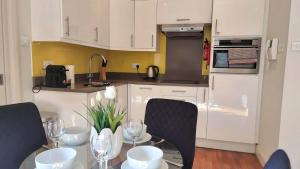 Una cocina con gabinetes blancos y una mesa con copas de vino. en Notting Hill - The One One One -2-, en Londres 18 fotos más