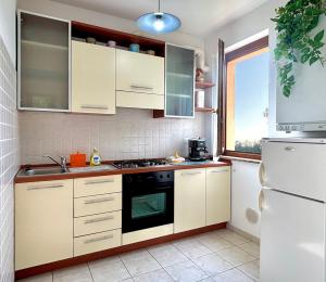 a kitchen with white cabinets and a stove top oven at Maison Peschiera in Sirolo +7 photos
