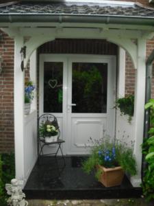 une porte d'entrée blanche d'une maison avec une chaise dans l'établissement Modernisierte Ferienwohnung Mit Balkon, à Schuby
