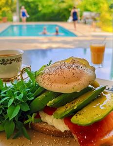 a sandwich with vegetables on a plate next to a pool at Le Mas Des Abeilles - Chambres d'hôtes en Drôme Provençale in La Bégude-de-Mazenc +53 photos