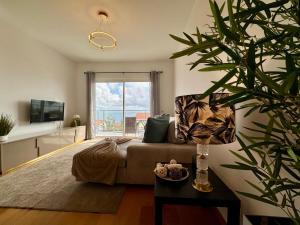 a living room with a couch and a large window at Welcome to Paradise Island in Caniço