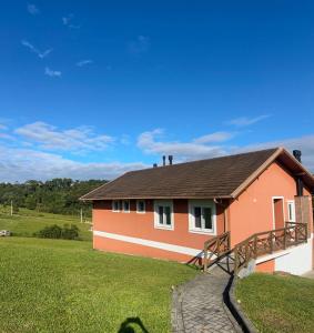 a orange house with a green field and blue sky at Casa em condomínio rural in Rancho Queimado