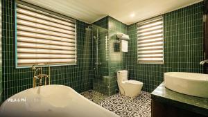 La salle de bains est pourvue de carrelage vert, d'une baignoire et de toilettes. dans l'établissement Biệt Thự HL Near Beach, à Hạ Long