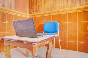 een laptop op een tafel met een blauwe stoel bij Hotel O Taman Wisata Iman Ii Near Taman Wisata Iman Sitinjo in Hutamanik