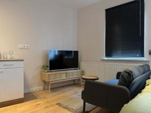 a living room with a couch and a flat screen tv at The Cozy Nest Stylish and Serene City Studio in Eindhoven