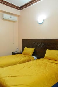2 camas en una habitación con sábanas amarillas en Hotel Yassmina, en Aourir