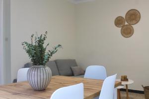 a vase on a wooden table with white chairs at Apto el Piset, acogedor y céntrico del Montseny in Arbúcies