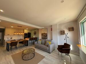 ein Wohnzimmer mit einem Sofa und Stühlen sowie eine Küche in der Unterkunft Apartamento los Remos VUT-3207AS in Llanes + 11 Fotos