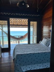 a bedroom with a bed and a view of the ocean at Aroeiraecocasa in Morro de São Paulo