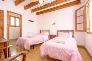 two beds in a room with white walls and wooden ceilings at Pensión Bellavista in Port de Pollensa