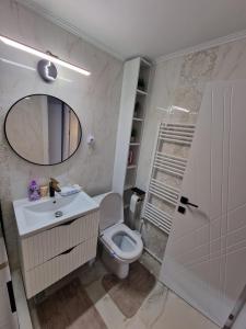 a bathroom with a toilet and a sink and a mirror at Cazare Buzau Lux in Buzău +3 photos