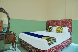 a bed with yellow and blue pillows in a room at Hotel O Romli in Rumpuktulunghoni