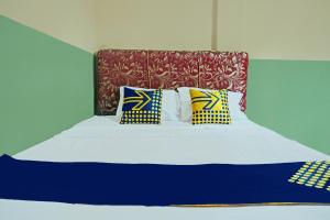 a bed with four pillows on top of it at Hotel O Romli in Rumpuktulunghoni